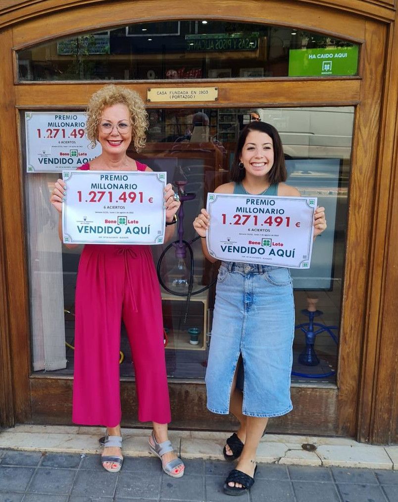 Imagen Maria Angeles y su hija Desirée en el exterior de su establecimiento con el cartel del premio millonario de la primitiva que han repartido.