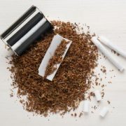 Máquina de liar y entubar con tabaco alrededor y cigarrillos preparados.